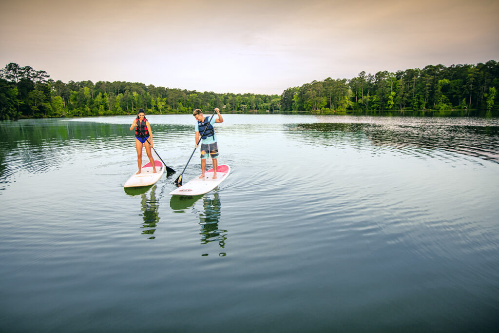 a woman and man paddle boarding on a lake