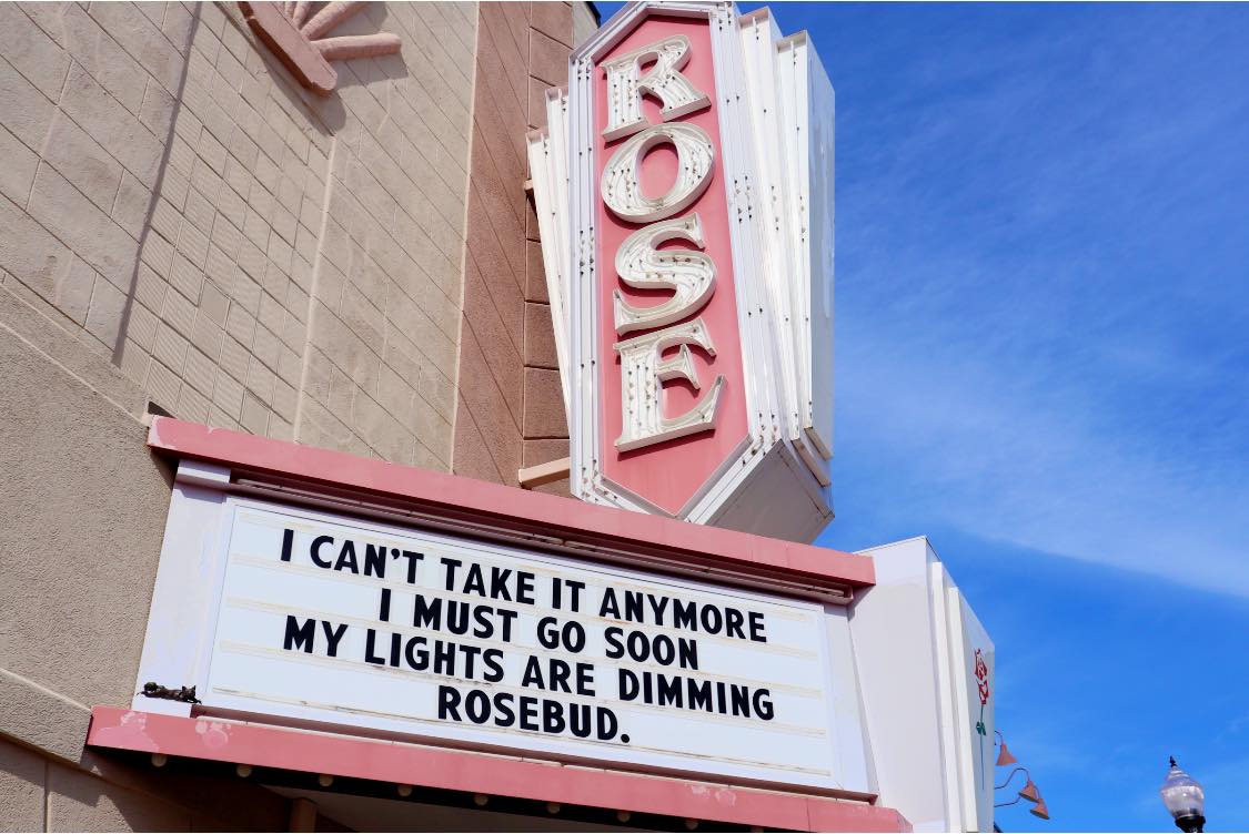 Close up image of the Historic lit-up "Rose" marquee on the outside of the Rose Theater building.