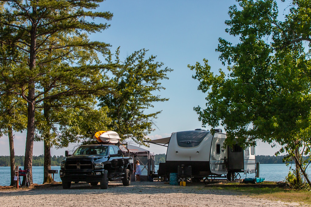 truck with kayaks mounted on top next to a RV parks on side of a lake