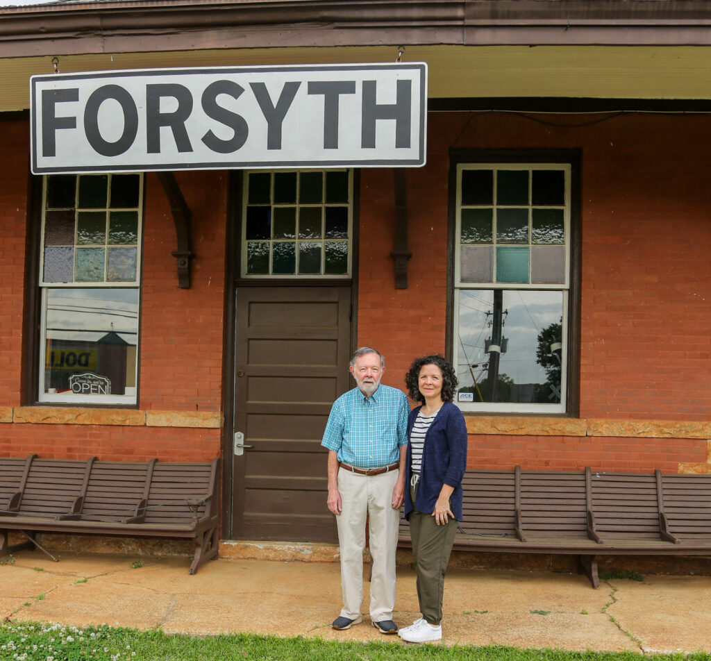 A couple posed in front of the Historical Society Museum and Train Depot in Forsyth, GA.