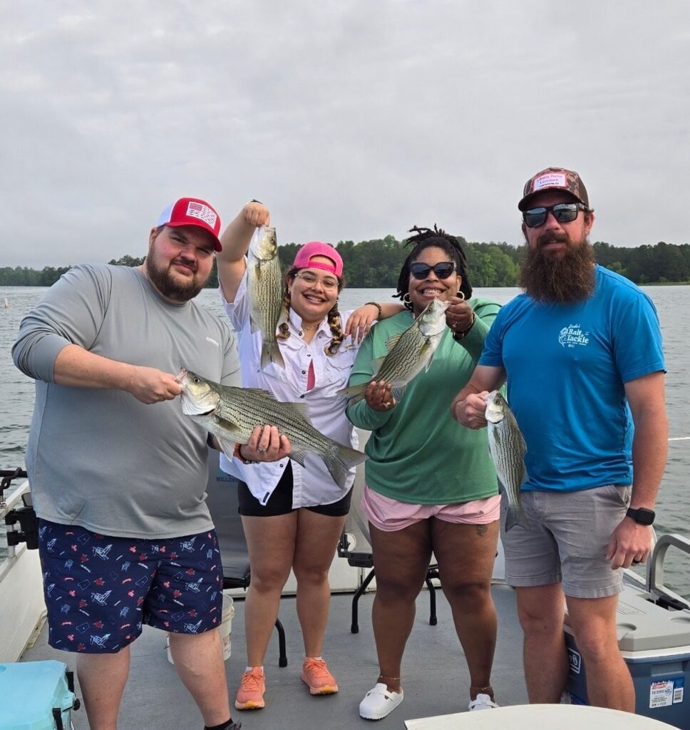 A group of guests on the All Seasons Guide Service tour holding the fish that they've just caught.