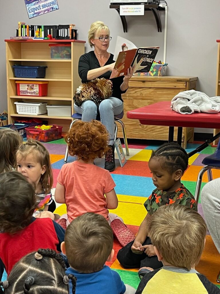A picture of Miss Happy doing story time at a local school with Elvis the rooster