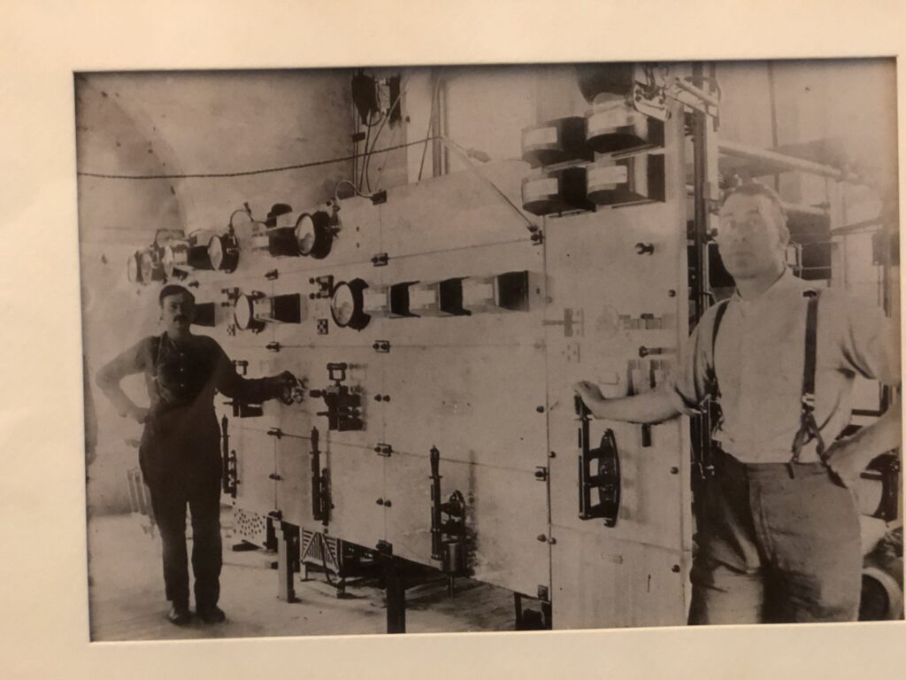 black and white photo of men standing in front of a large electrical machine
