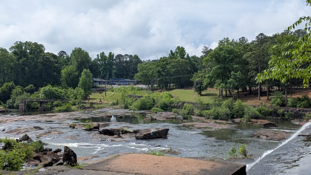 river with large rocks and boulders peaking through and trees in distance