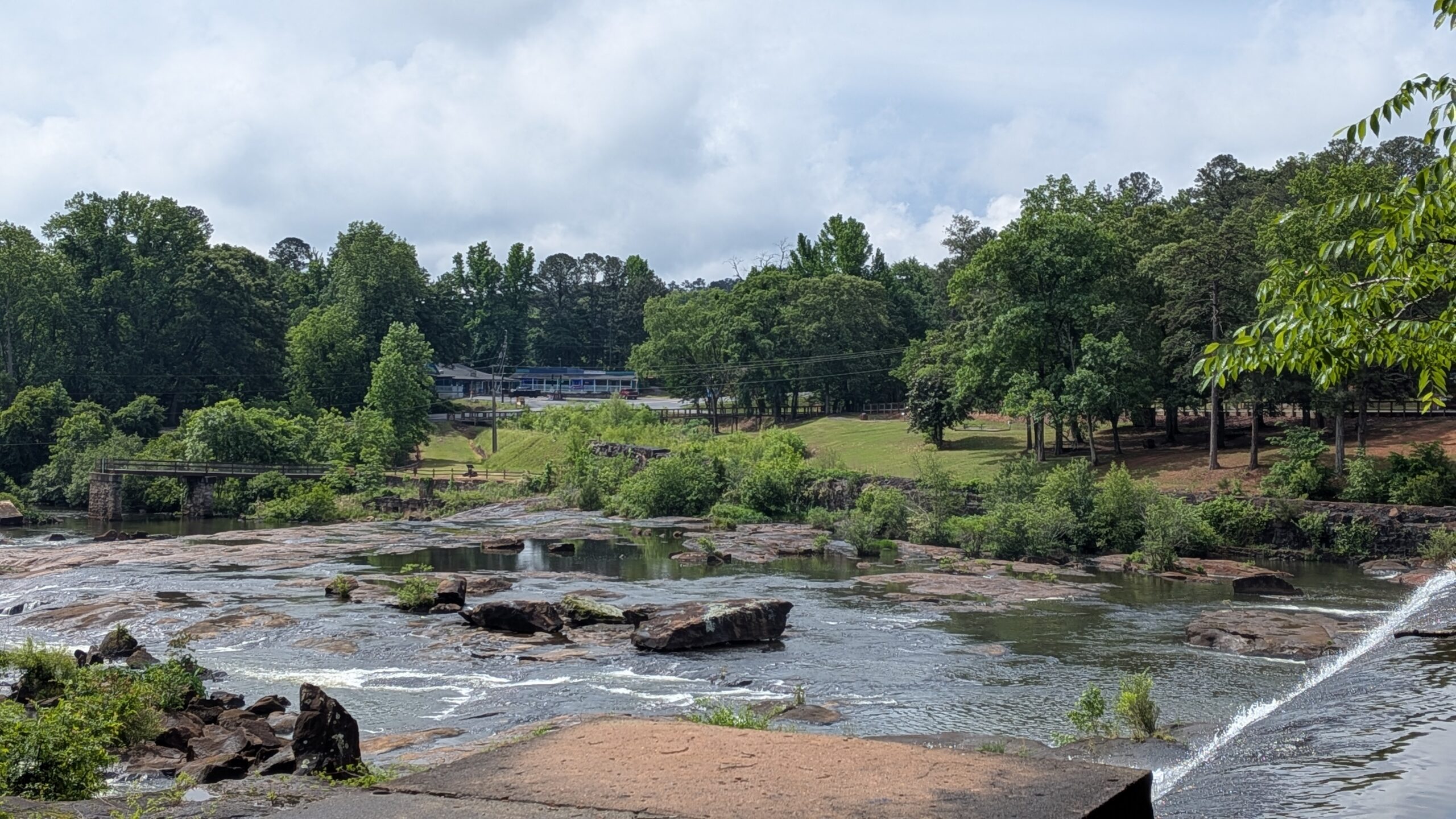 river with large rocks and boulders peaking through and trees in distance