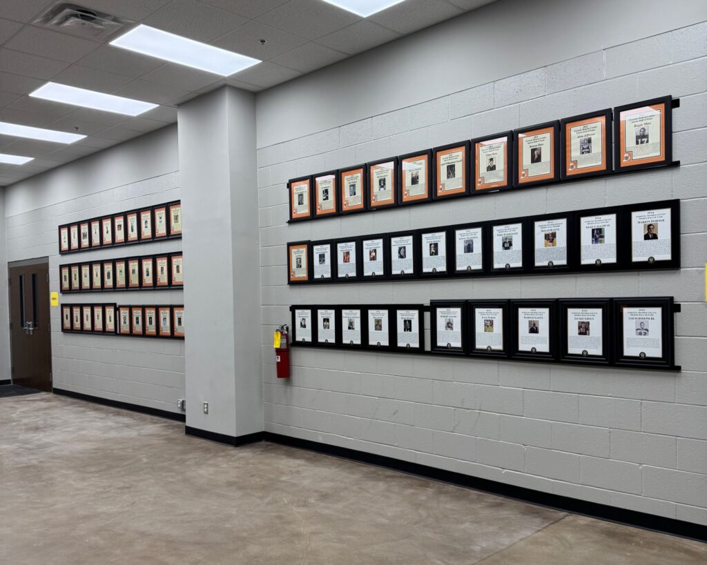white brick wall with three rows of framed plaques