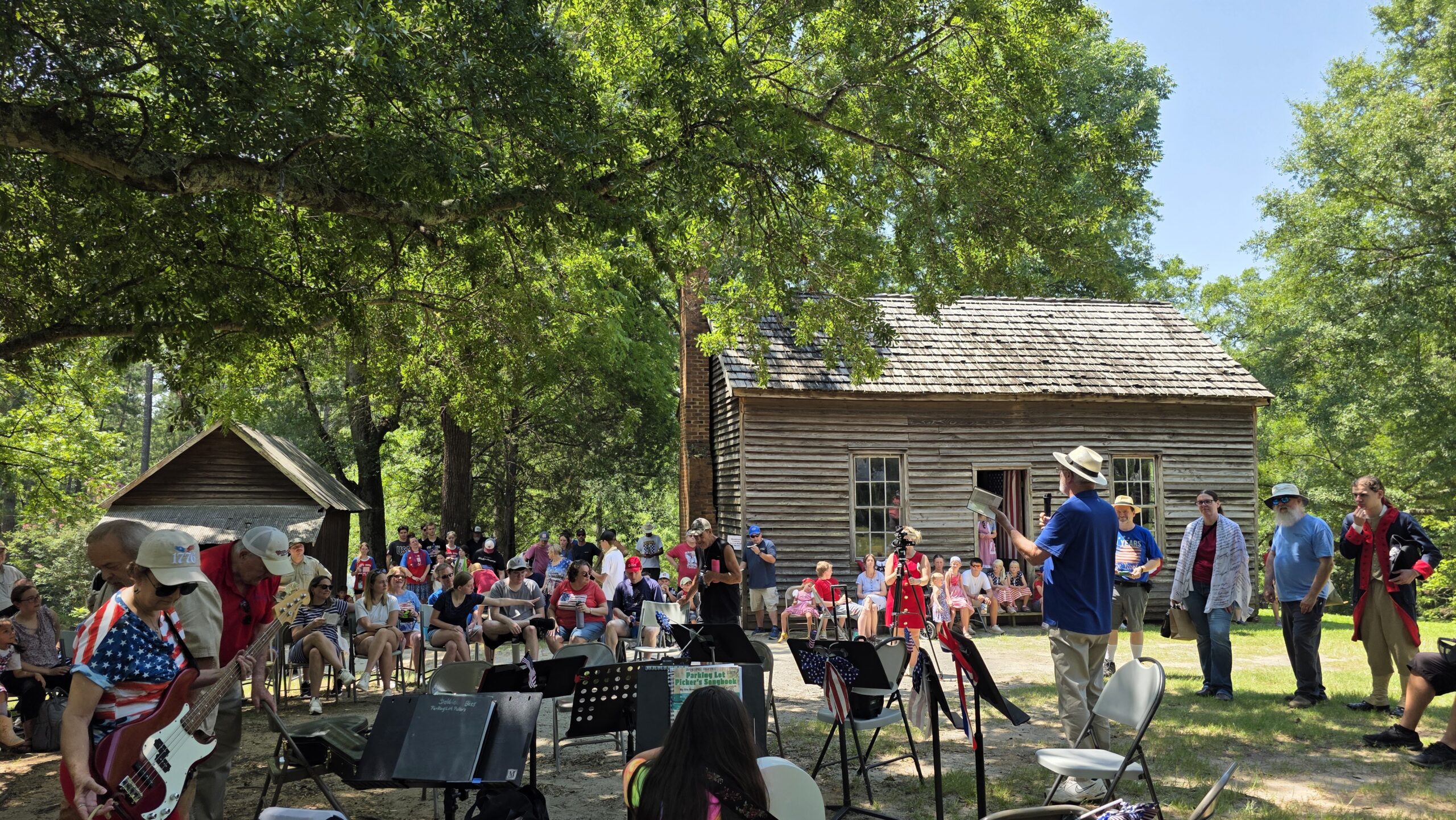 crowd gathers in front of old wooden cabin