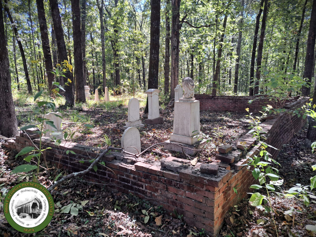 grave markers among trees with low brick fencing around