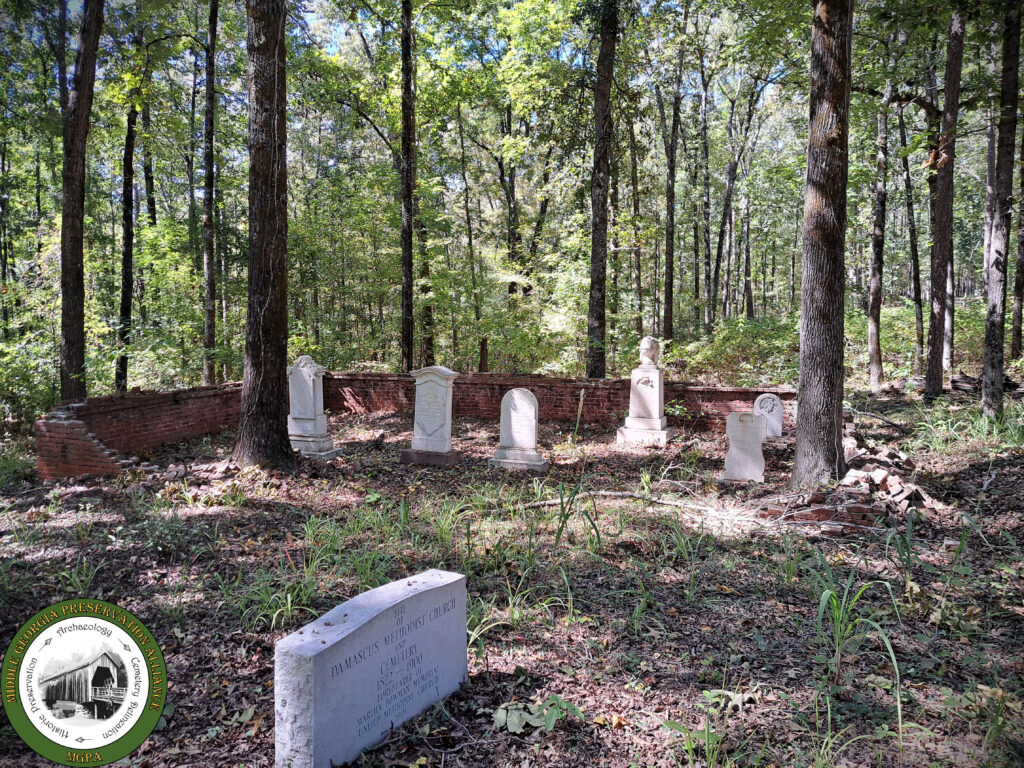 grave markers among trees with low brick fencing around