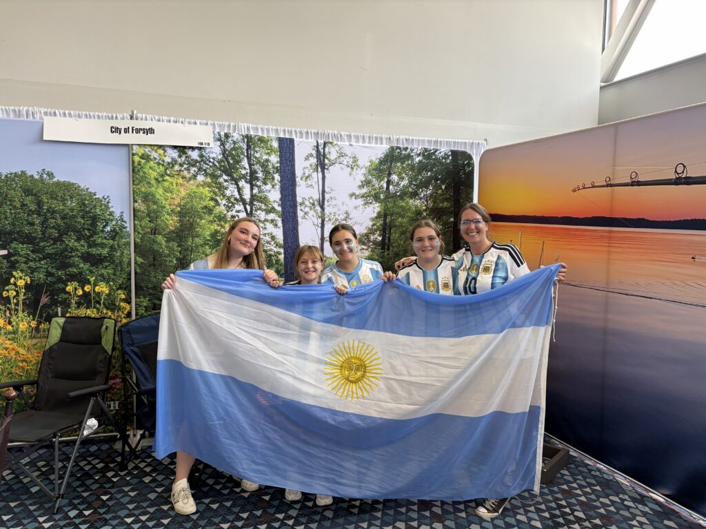 Family poses with Argentina flag in the Visit Forsyth GA booth