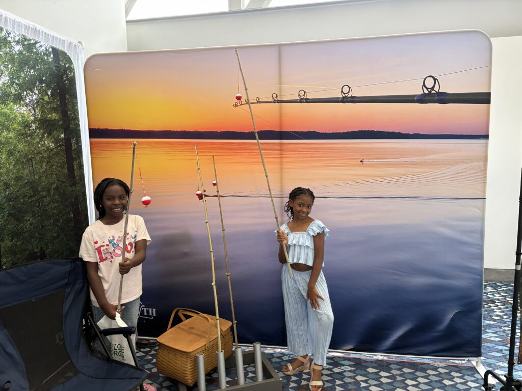 girls pose with cane fishing poles in Visit Forsyth GA booth