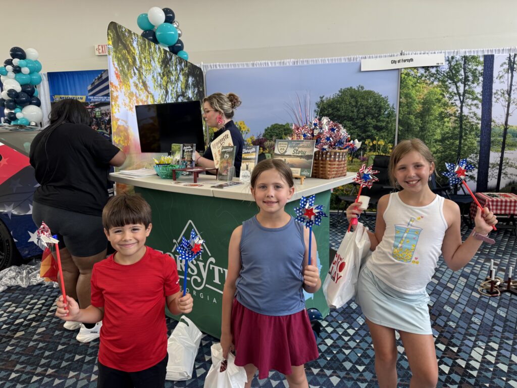 Kids pose with pinwheels in front of Visit Forsyth GA booth