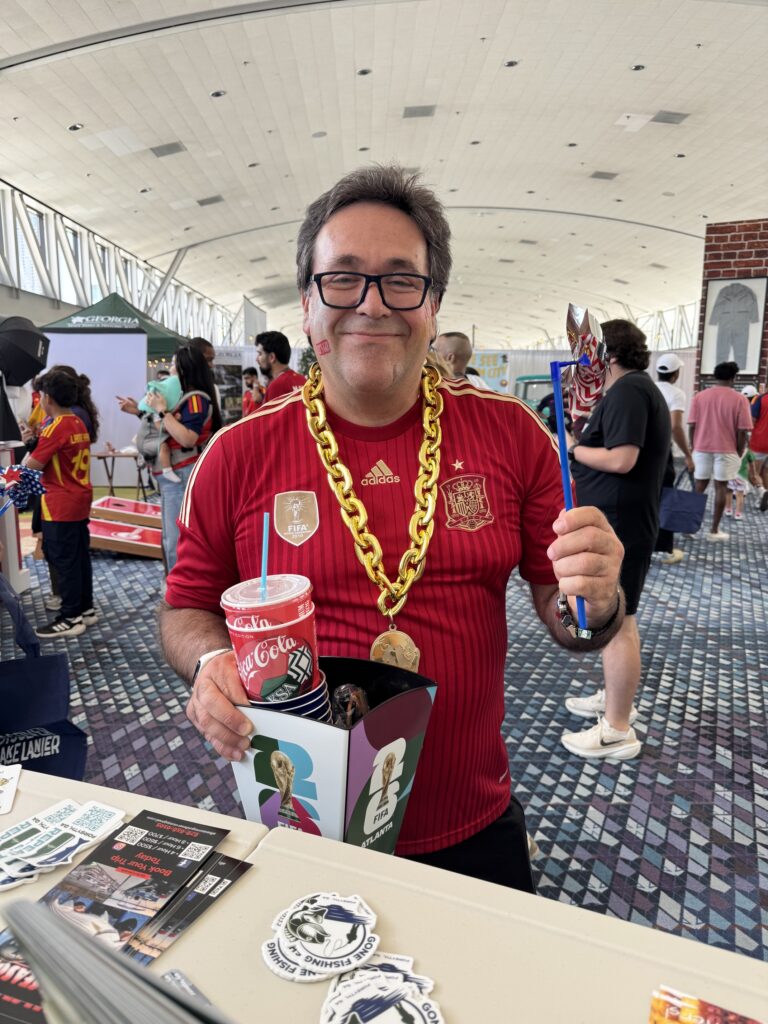 world cup fan holds pinwheel in front of Visit Forsyth GA booth