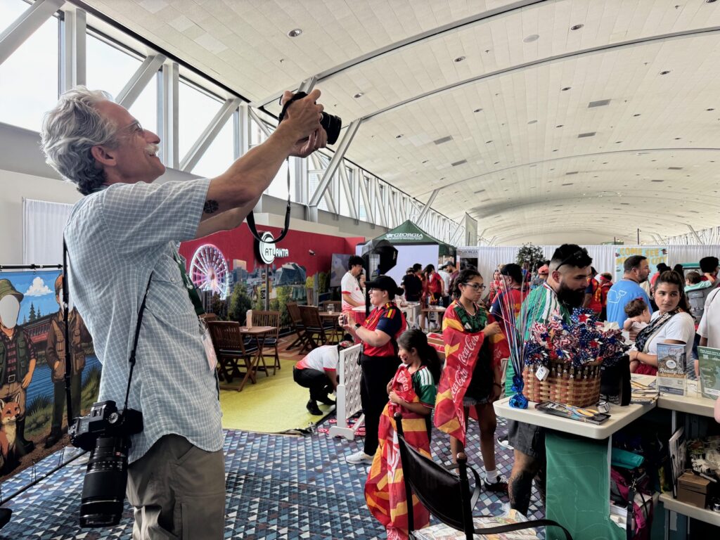 photographer stands behind Visit Forsyth GA booth to caption crowd aerial shot