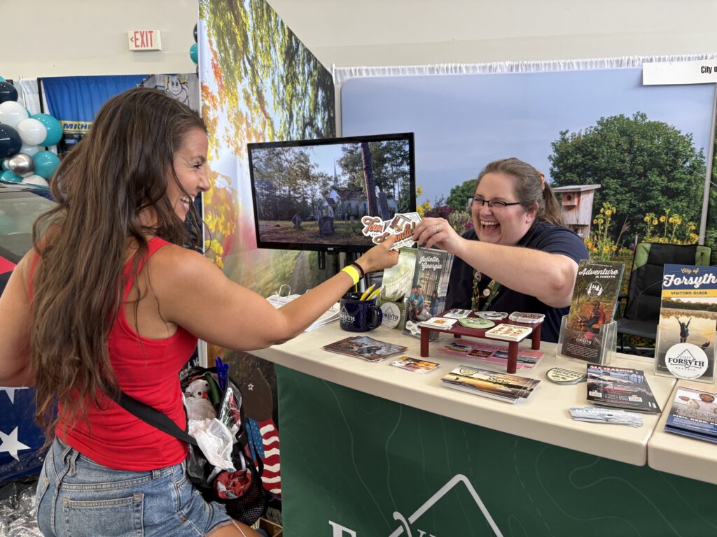 Visit Forsyth GA staff person hands Towanda sticker to Fried Green Tomatoes fan