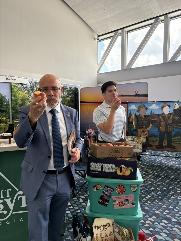Swedish diplomat eats a peach at Visit Forsyth GA booth