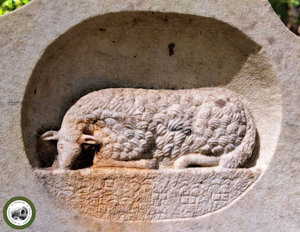 large grave monument with carving of a sheep lying down