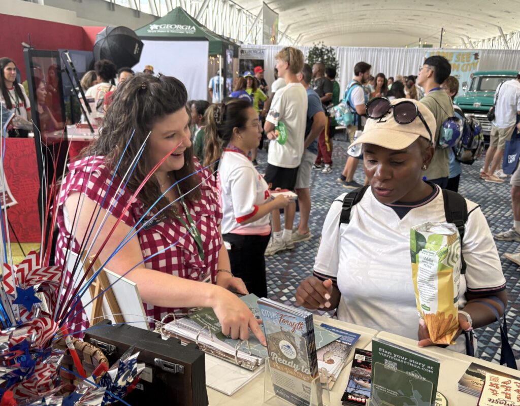 one lady points to a map helping another lady at information booth
