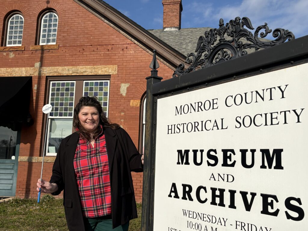 Nicole Newsom beside the Monroe County History Museum sign.